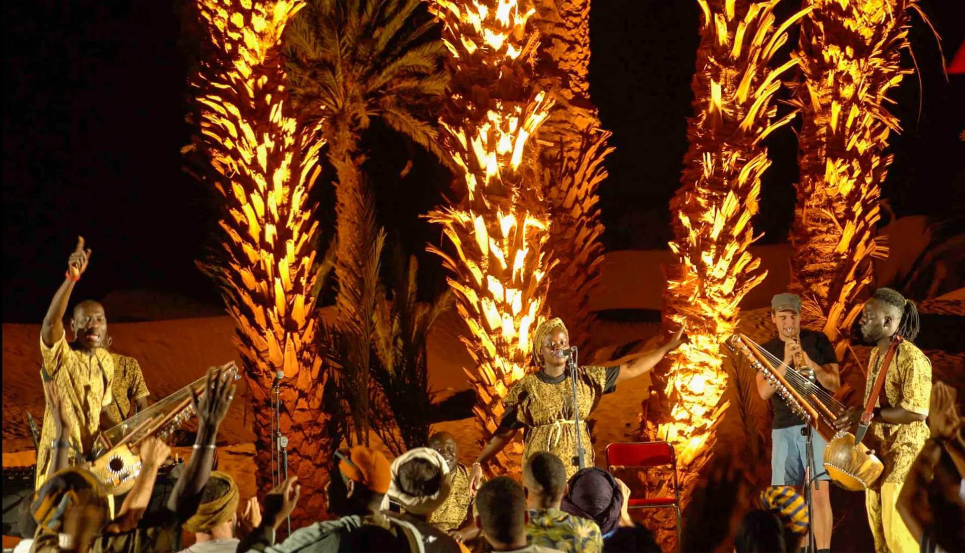 Concert nocturne sous les palmiers illuminés lors du Festival Zamane 2025, avec la chanteuse Oum